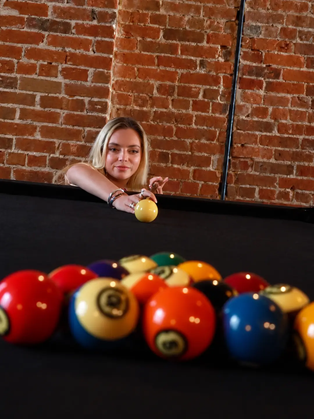 Blonde woman at the pool table behind racked balls
