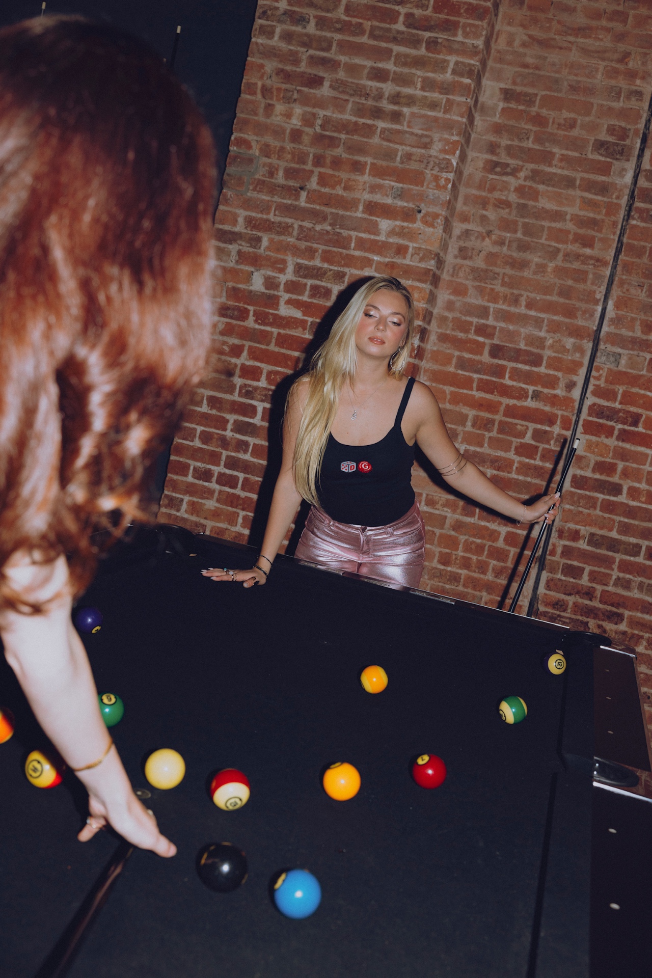 Blonde in a black Drink & Gamble tank at the pool table